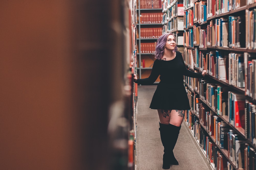 woman standing in middle of bookshelves
