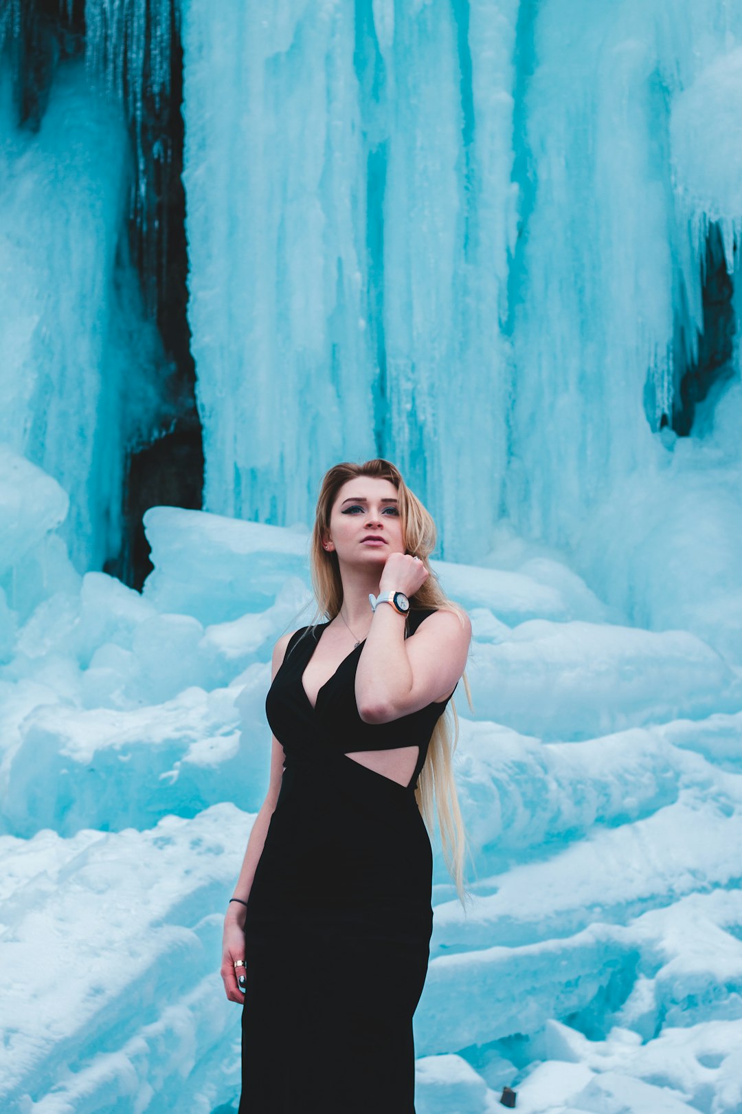 woman standing near ice wall wearing black sleeveless dress