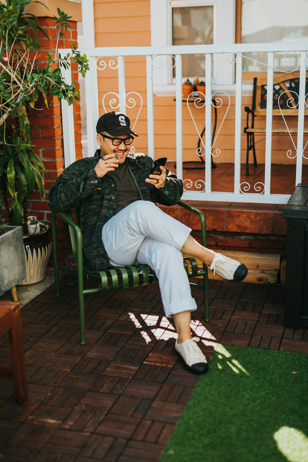 laughing man sitting on chair while using smartphone