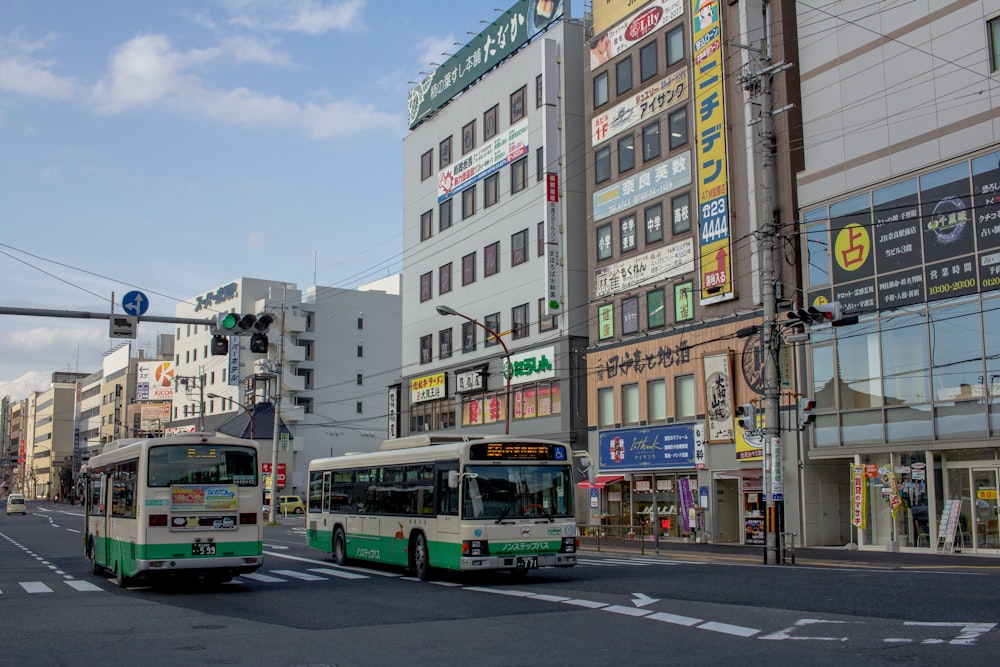 two white-and-green buses on road during daytime