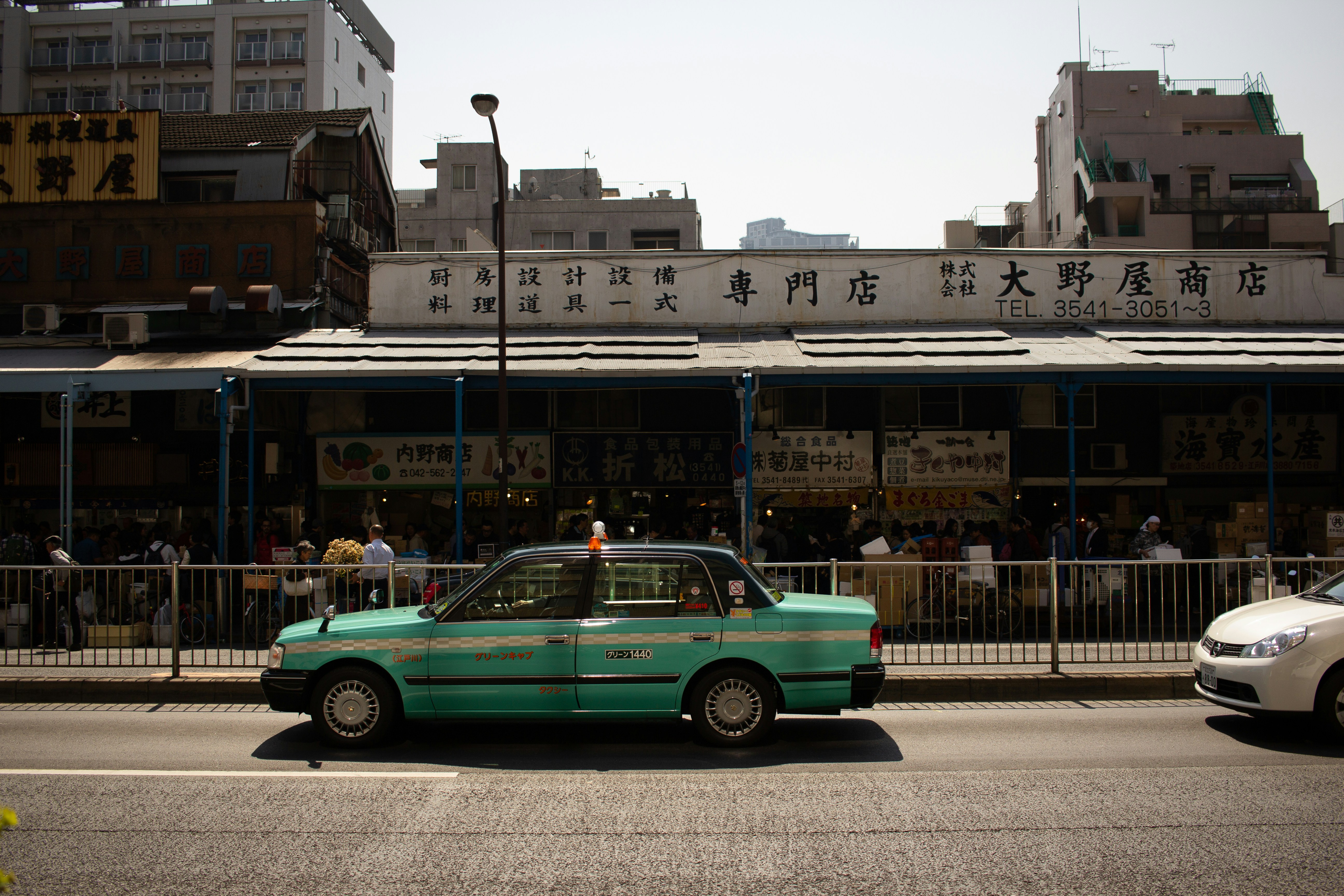 A taxi drives in front of a market in Japan.