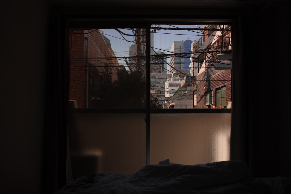 a bedroom with a view of a city outside the window