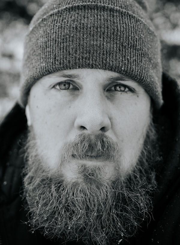 grayscale photography of man jacket and knit cap