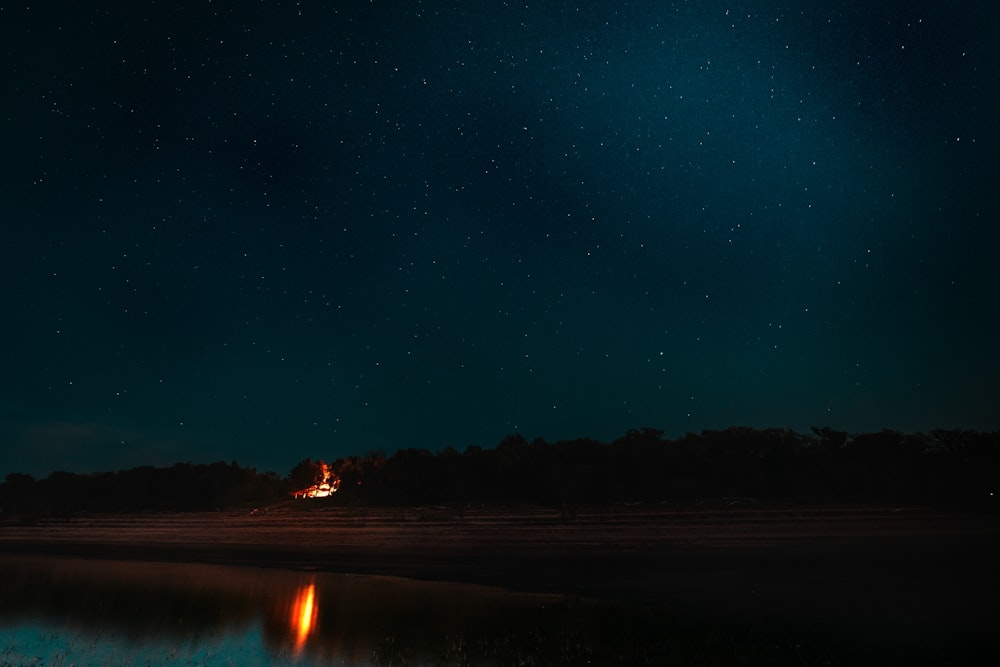 the night sky with stars above a body of water