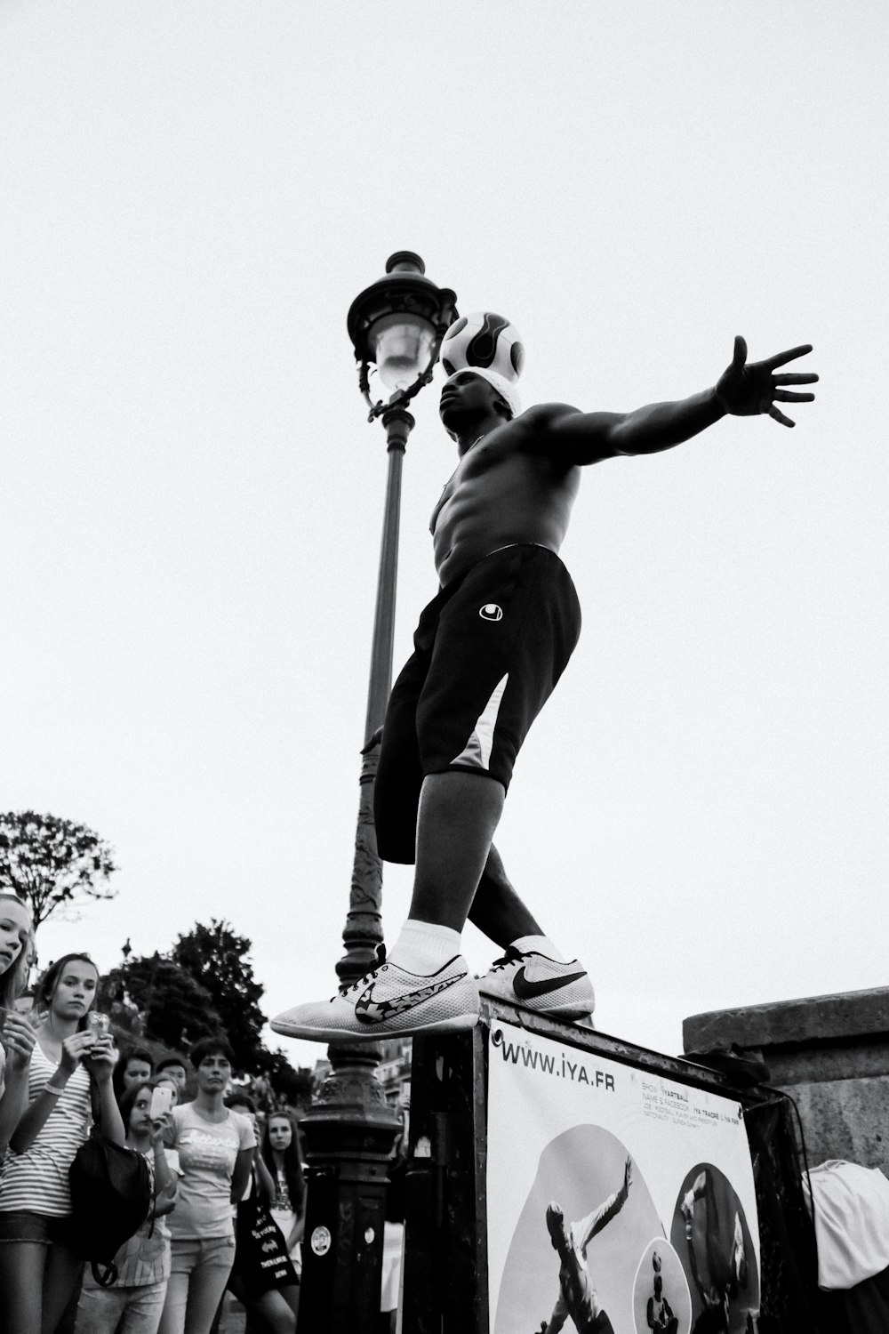 grayscale photography of person standing beside lamp post