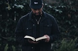 man in black jacket holding book