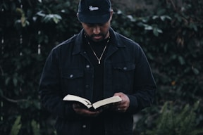 man in black jacket holding book