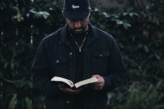 man in black jacket holding book