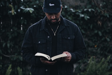 man in black jacket holding book
