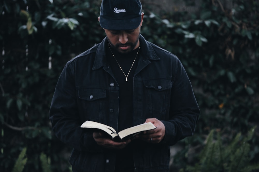 Mann in schwarzer Jacke hält Buch in der Hand