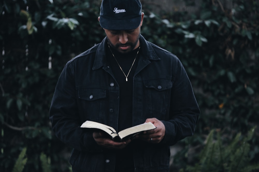 man in black jacket holding book
