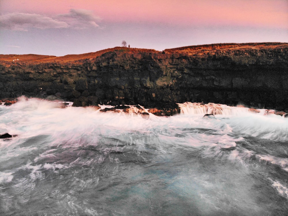 body of water beside cliff