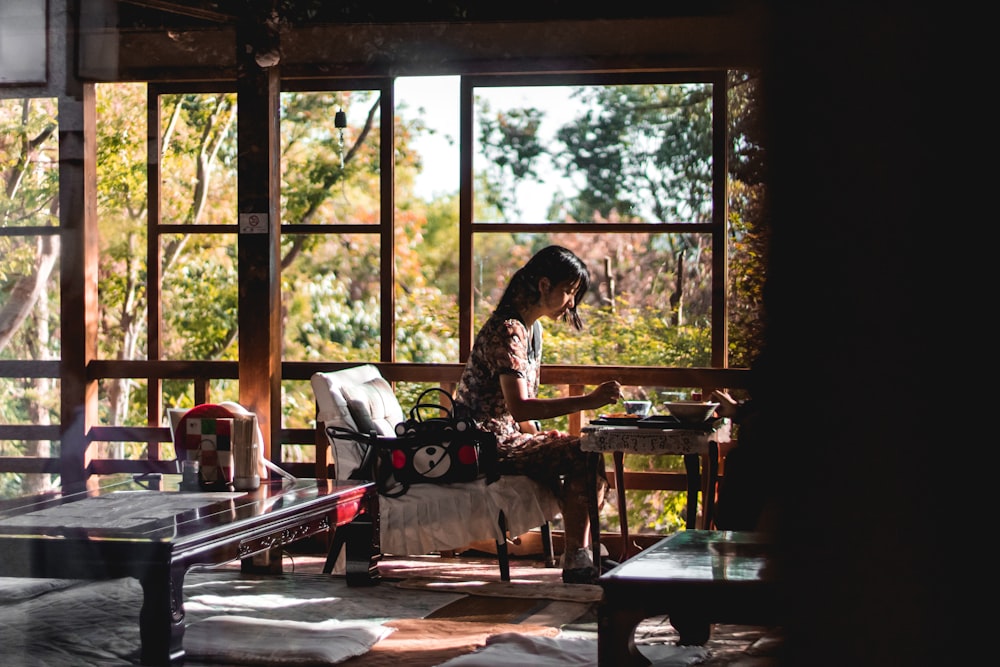 woman sits and about to eat beside window