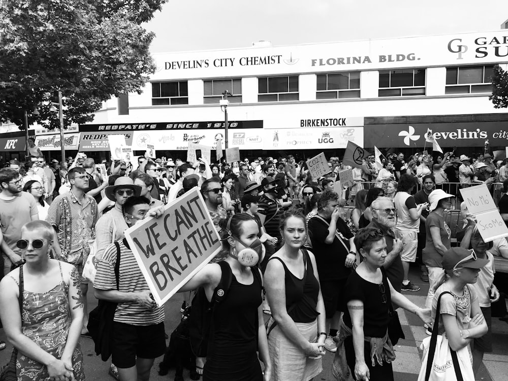 Fotografía en escala de grises de personas en una manifestación de protesta cerca de un edificio durante el día