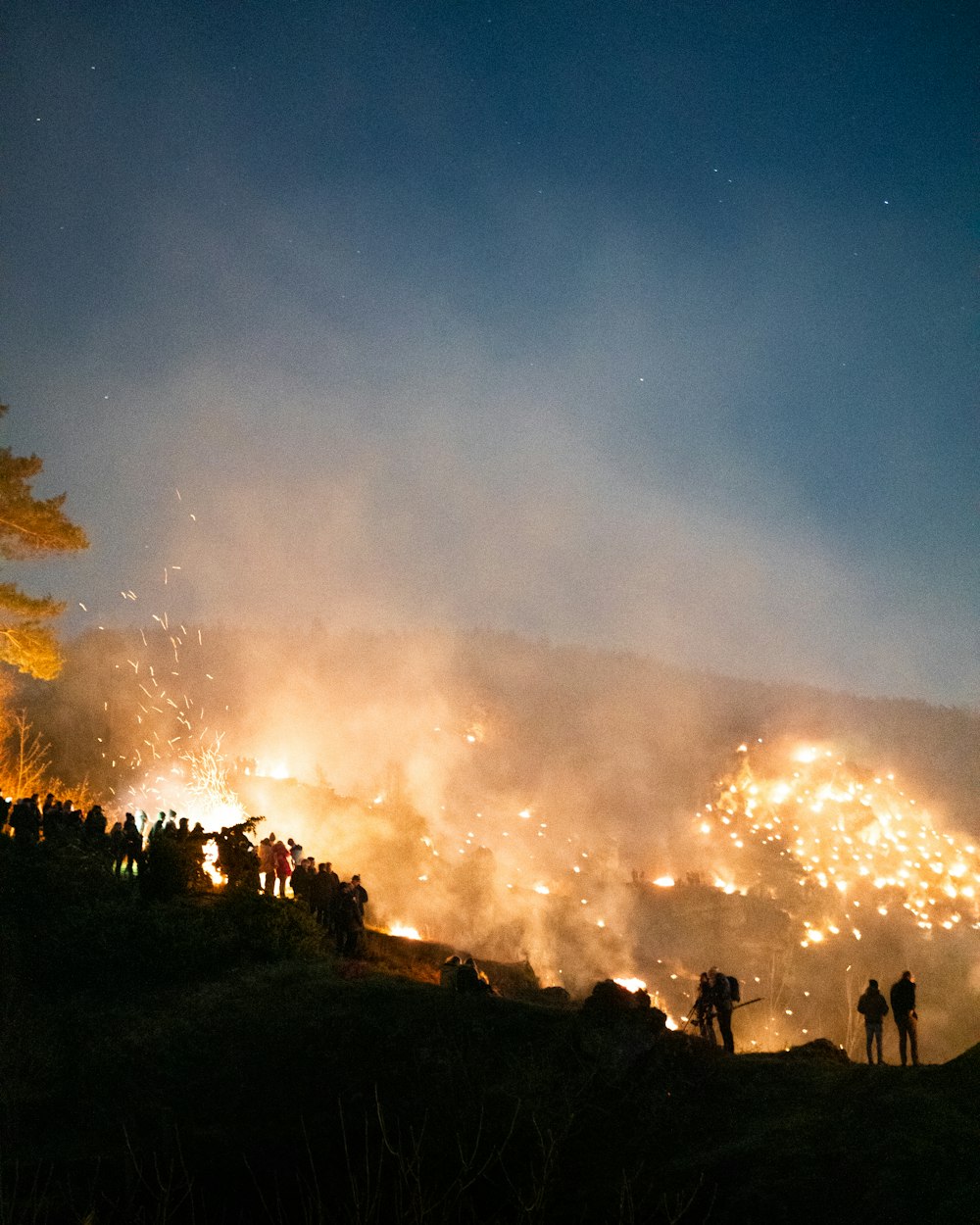 people standing on mountain near bush fire