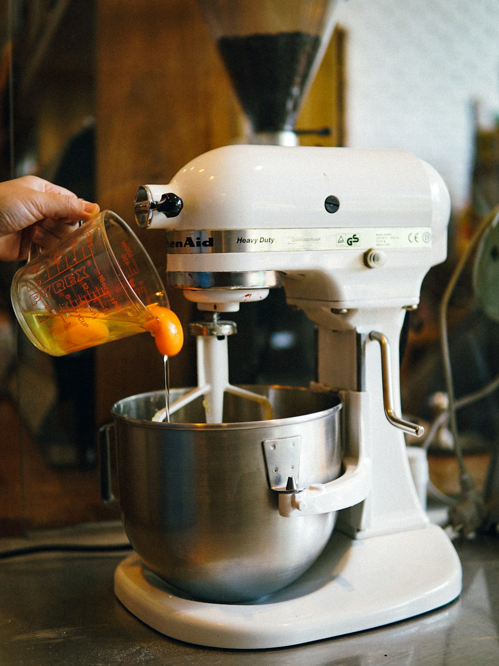 person pouring egg yolks on white stand mixer