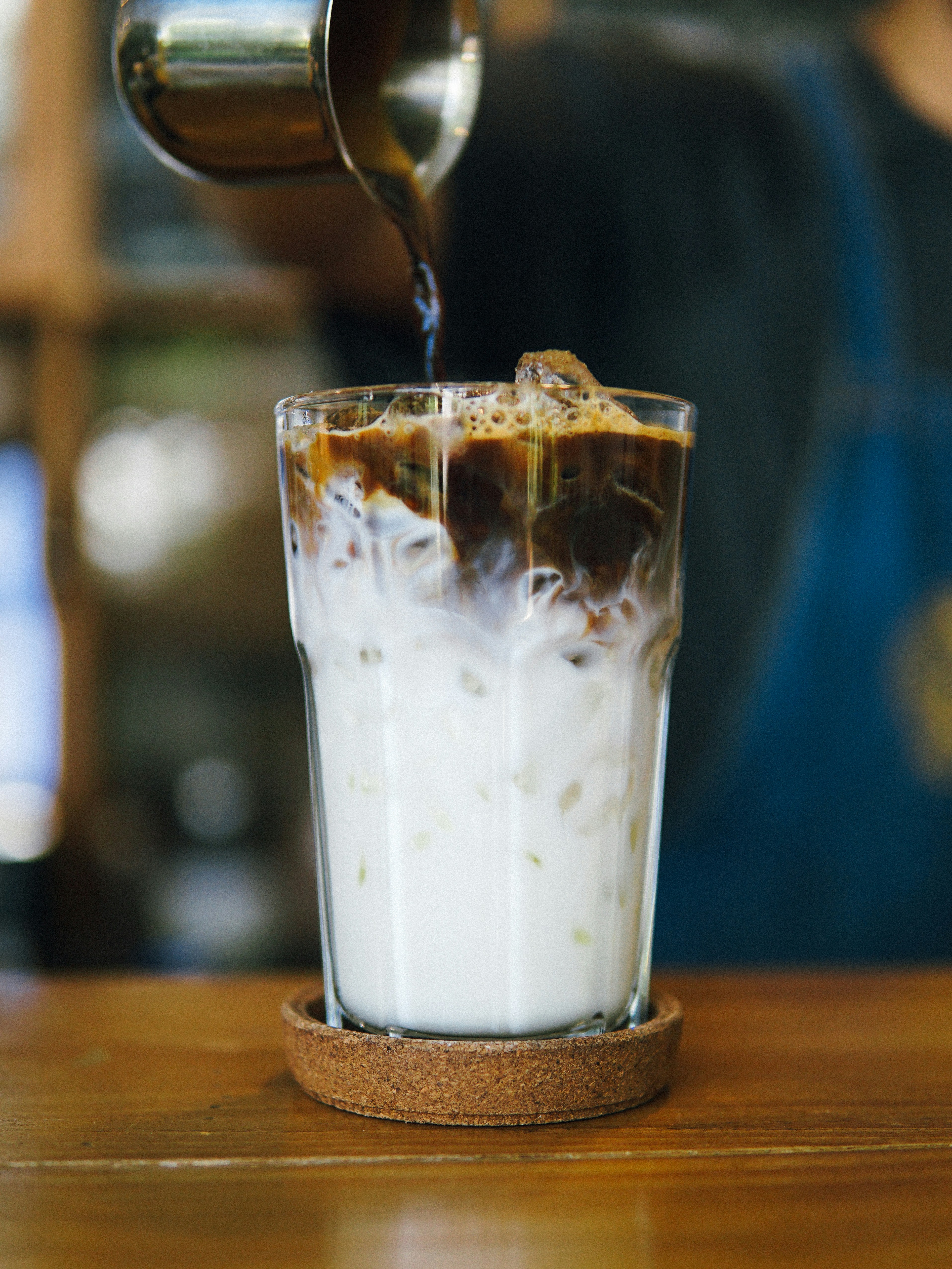 milk and coffee drink in drinking glass placed on cork coaster