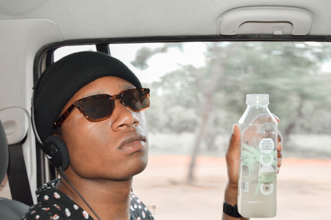 man inside vehicle holds beverage bottle
