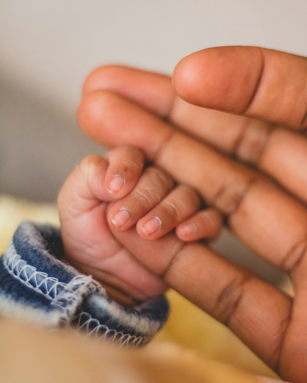 child's hand gripping person's pinkie finger