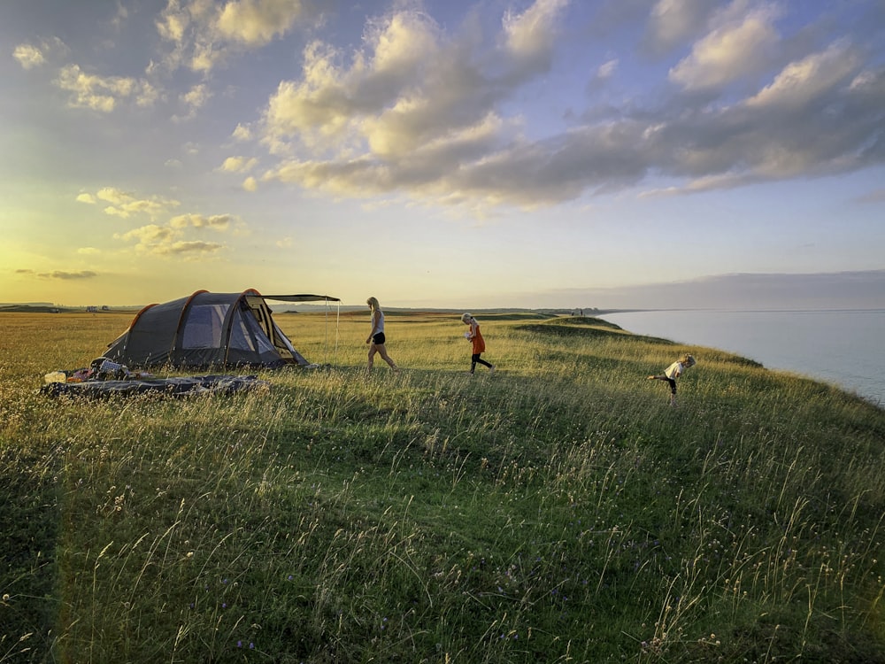 Kleinkind, das während der goldenen Stunde auf grünem Gras mit aufgebautem Zelt läuft