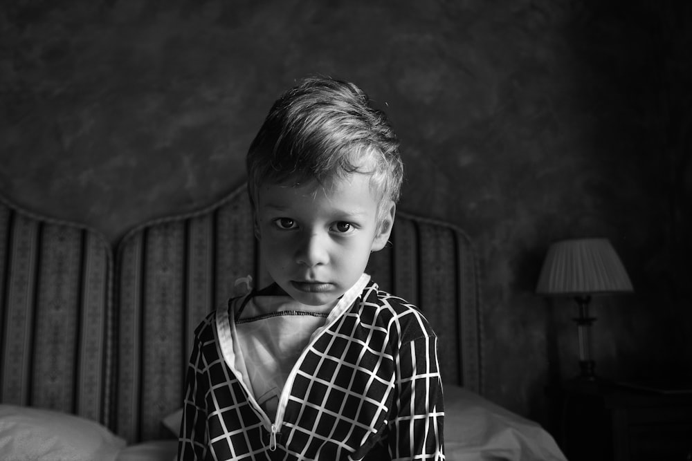 grayscale photography of boy on bed