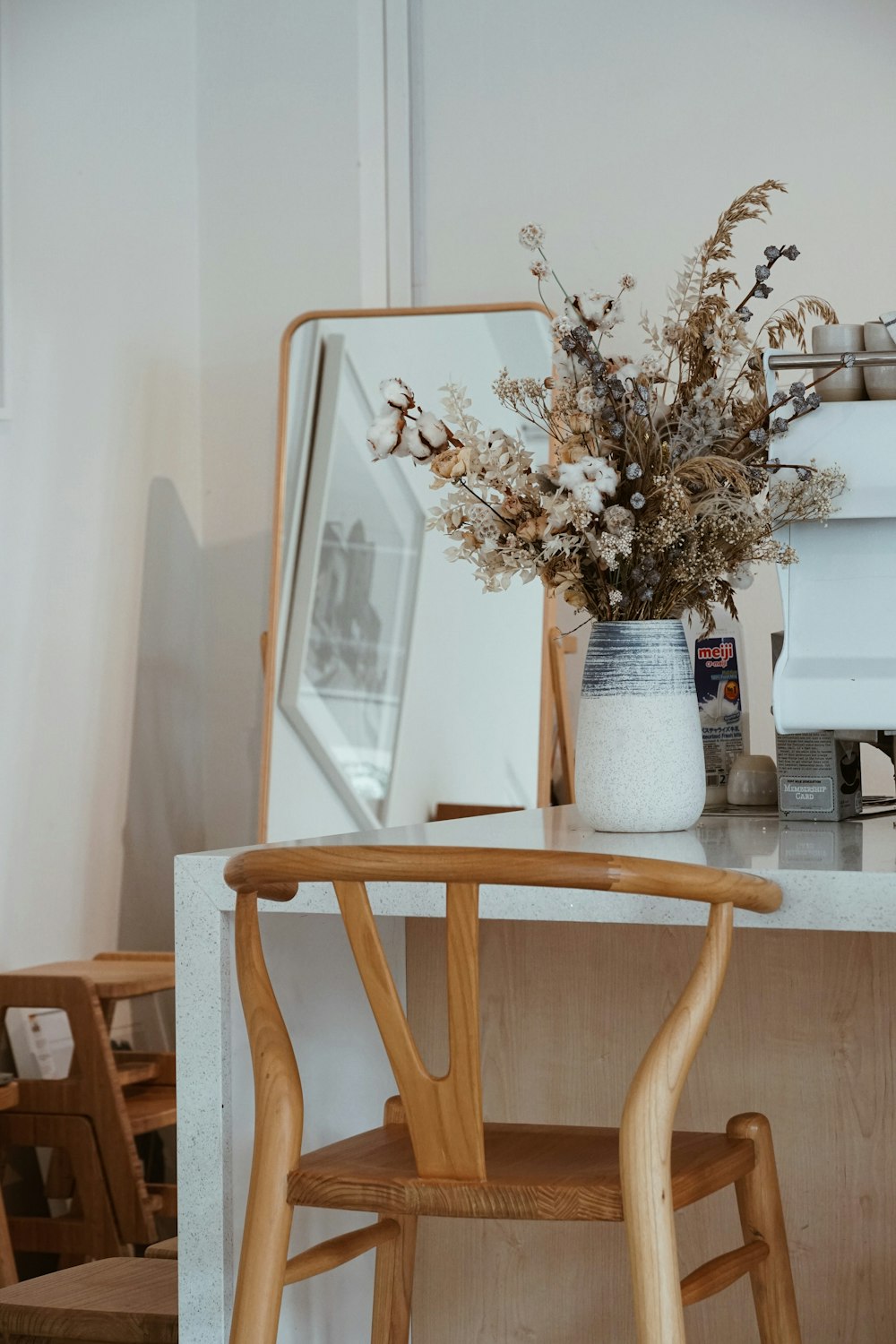 vase with flowers on white desk beside cheval mirror