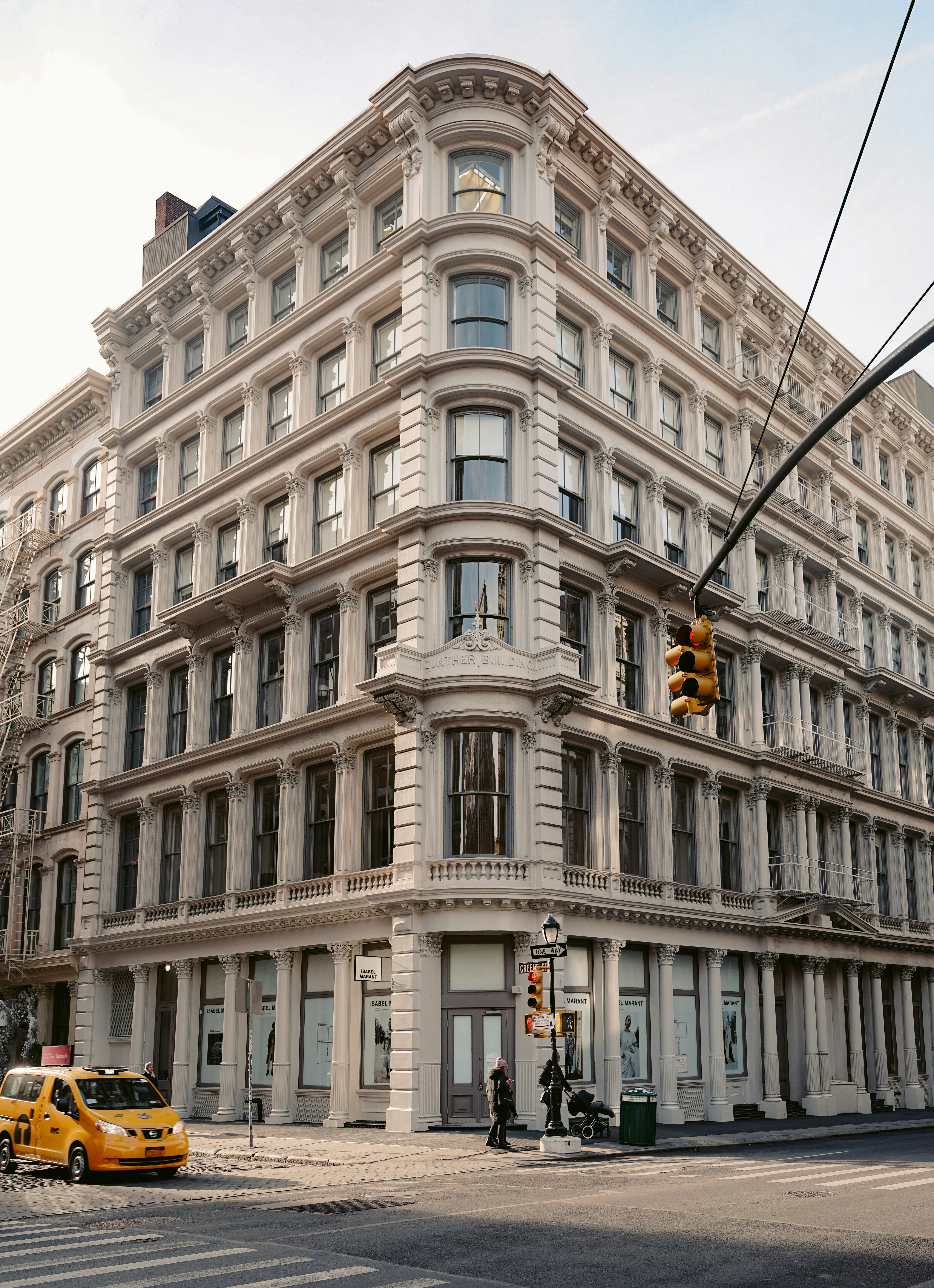 yellow taxi parked beside white building