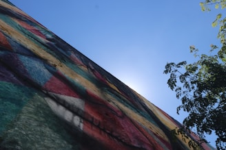 A vibrant mural depicting a sun surrounded by abstract shapes on a city wall.