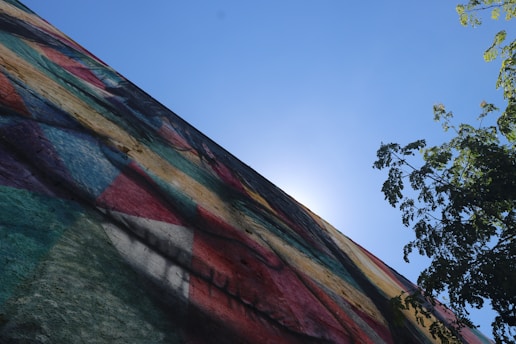A vibrant mural depicting a sun surrounded by abstract shapes on a city wall.