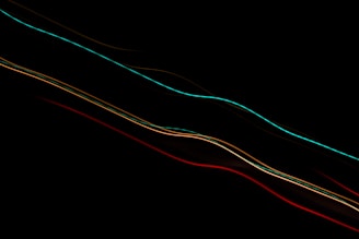 Bright, colorful light trails streak diagonally across a black background, creating a sense of motion and energy.