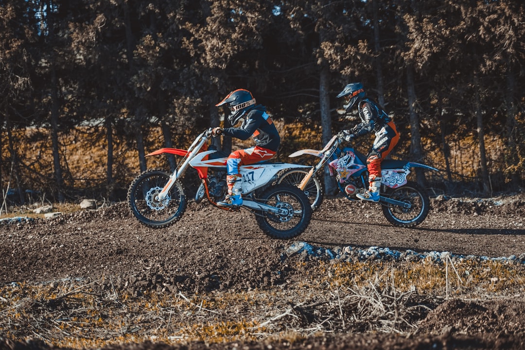 shallow focus photo of person riding motocross dirt bike during daytime