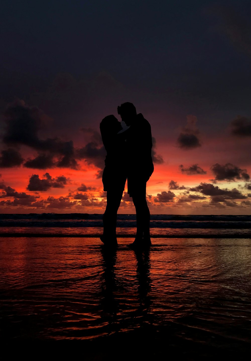 silhouette of man and woman hugging on shore