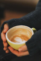 Close-up of hands gently holding a steaming cup of coffee, symbolizing warmth and connection.