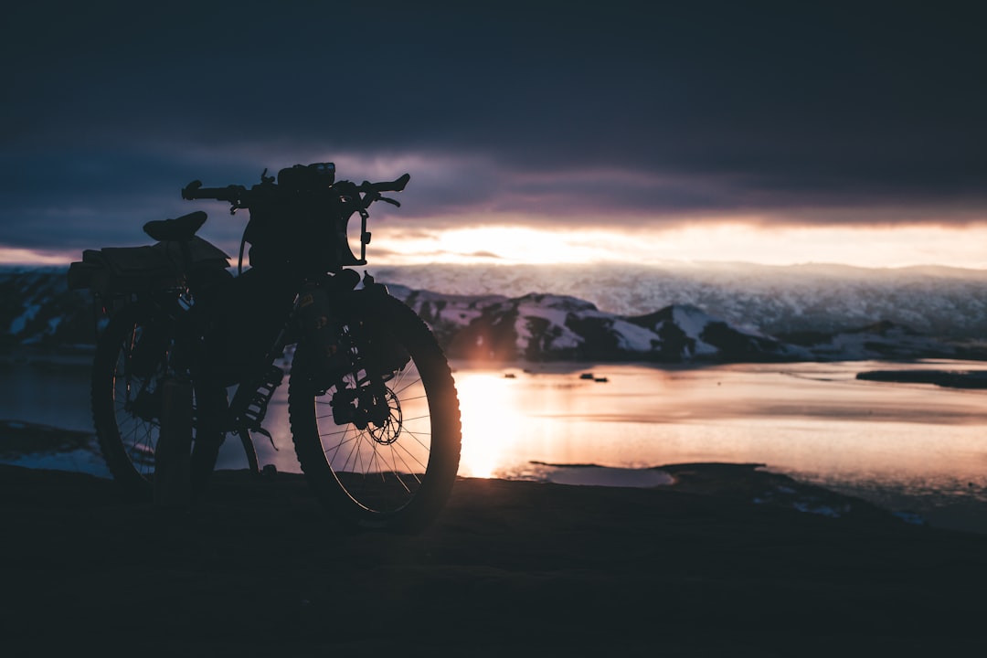 motorcycle park near body of water under dark clouds