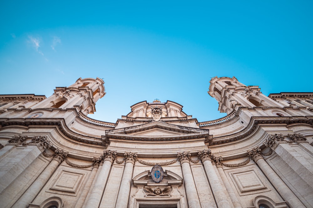 Low-Angle-Fotografie eines beigefarbenen Betongebäudes unter einem ruhigen blauen Himmel