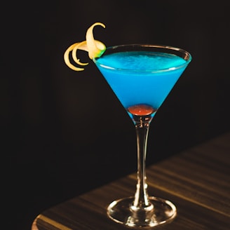 blue drink in wine glass on corner of wooden table