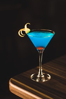 blue drink in wine glass on corner of wooden table