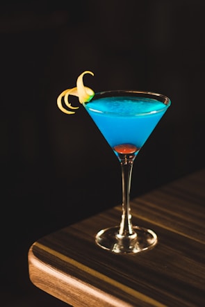 blue drink in wine glass on corner of wooden table