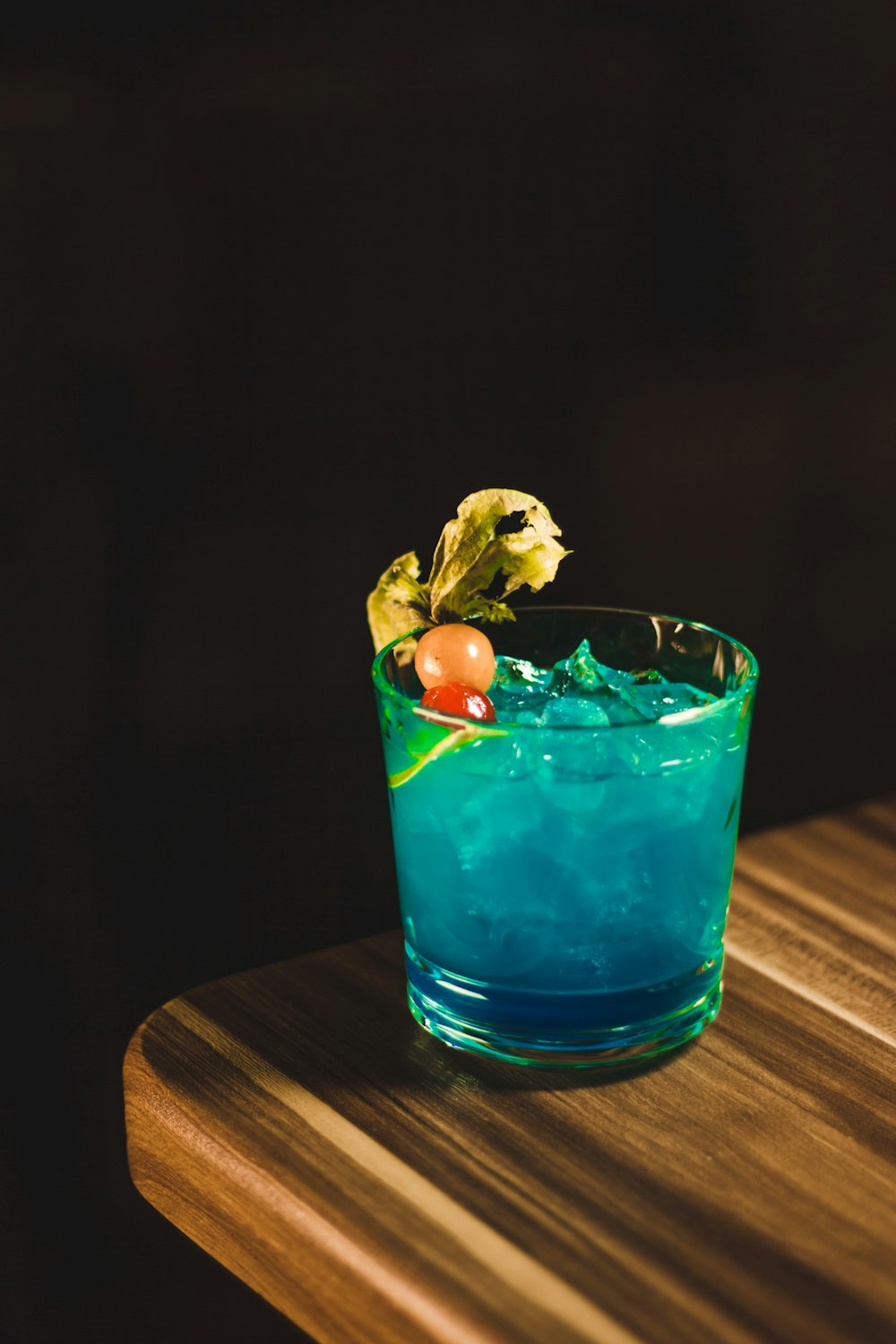 a blue cocktail sitting on top of a wooden table