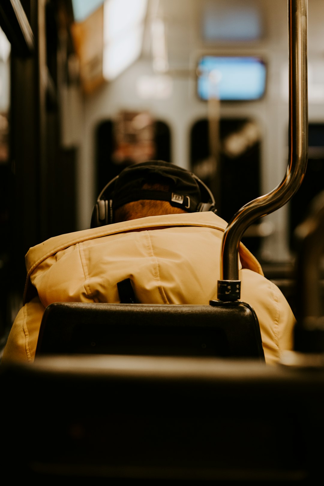 person wearing brown hooded jacket using black headphones while sitting on gray chair