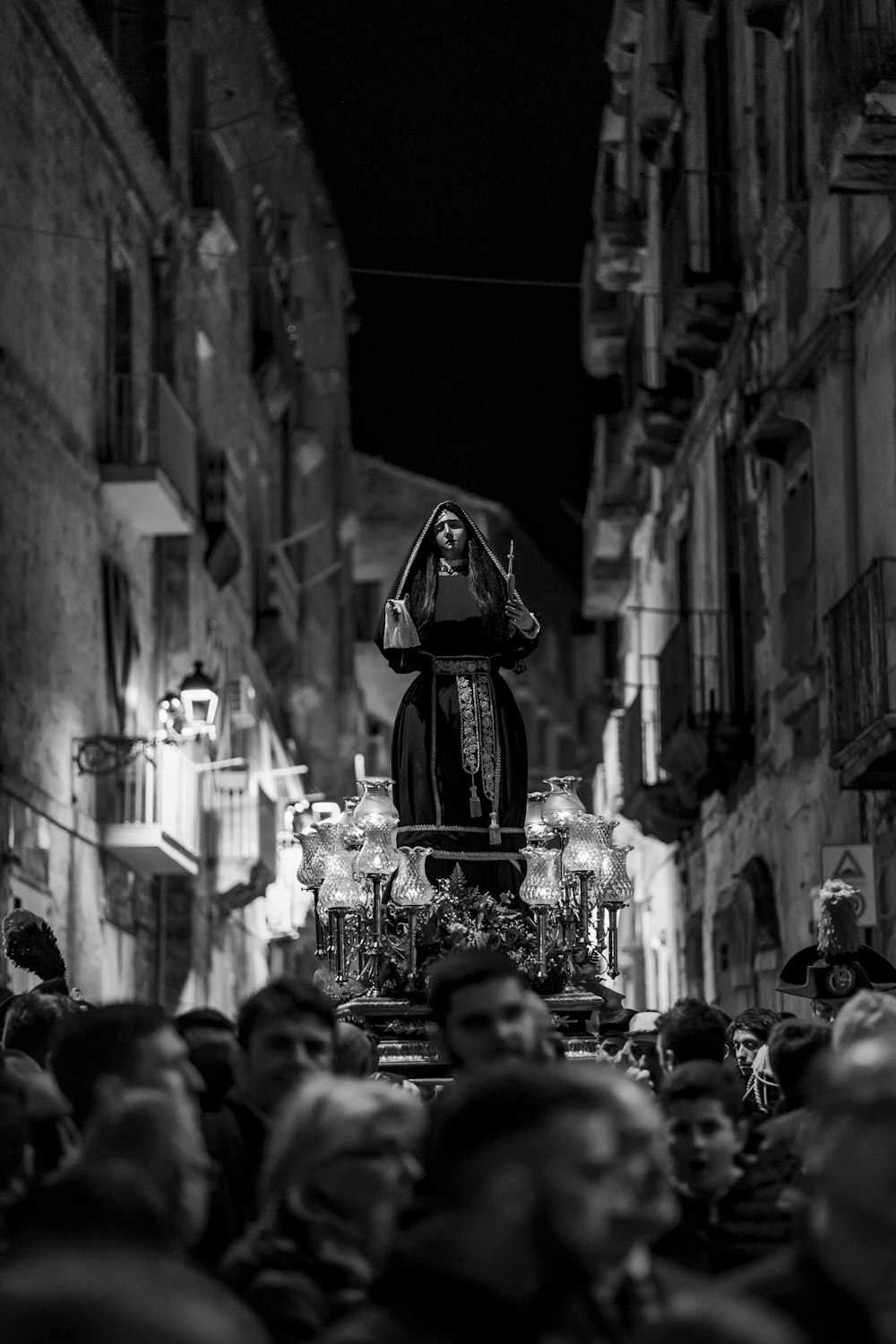 Photographie en niveaux de gris d’un groupe de personnes portant une statuette religieuse