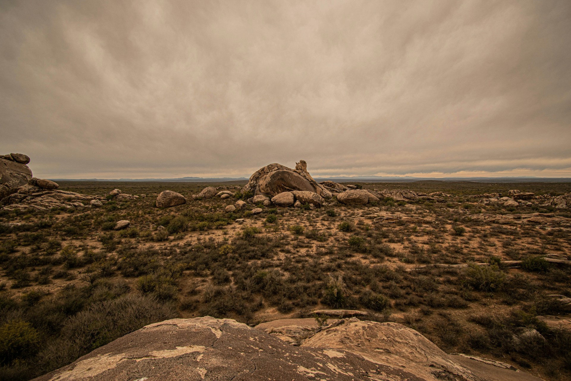 landscape photography of brown rocks on field under gray sky