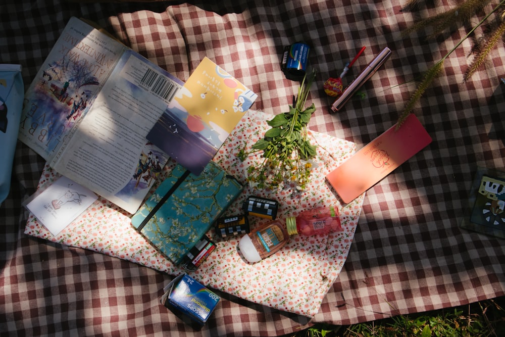 flowers and books on gingham sheet on grass