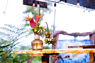 A rustic wooden table adorned with several garden lamps illuminating fresh flowers.