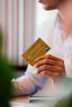 Close-up of a hand holding a gold membership card with a blurred travel scene in the background.