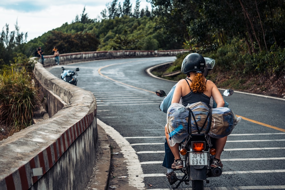man and woman riding motorcycle on roadway