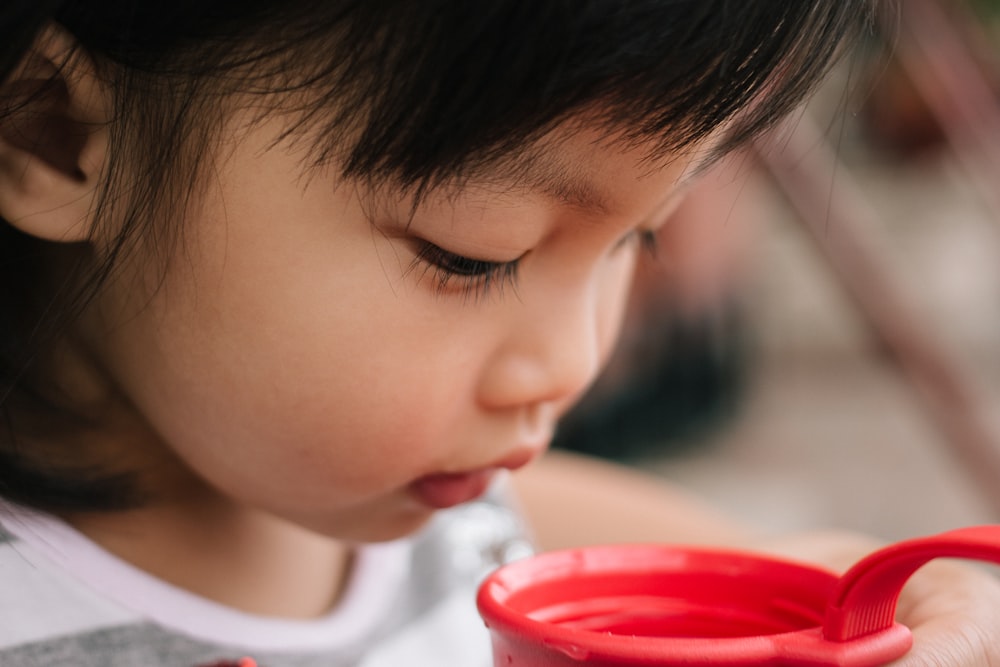 a little girl holding a red cup in her hands