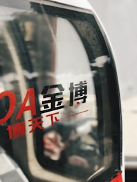 Chinese characters are printed in red and black on a glass surface, with an abstract blurred background visible through the glass.