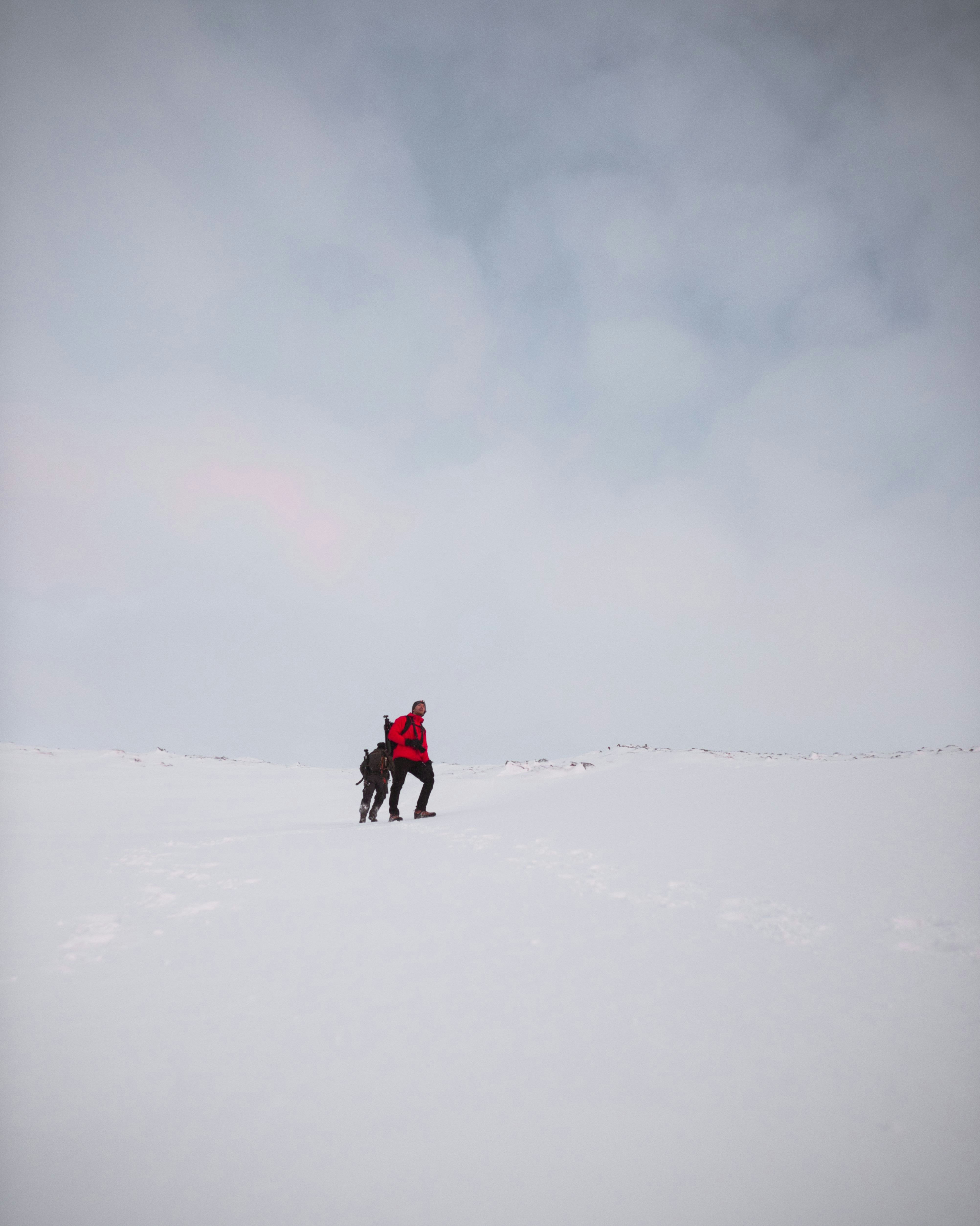 two men on snow field under cloudy sky