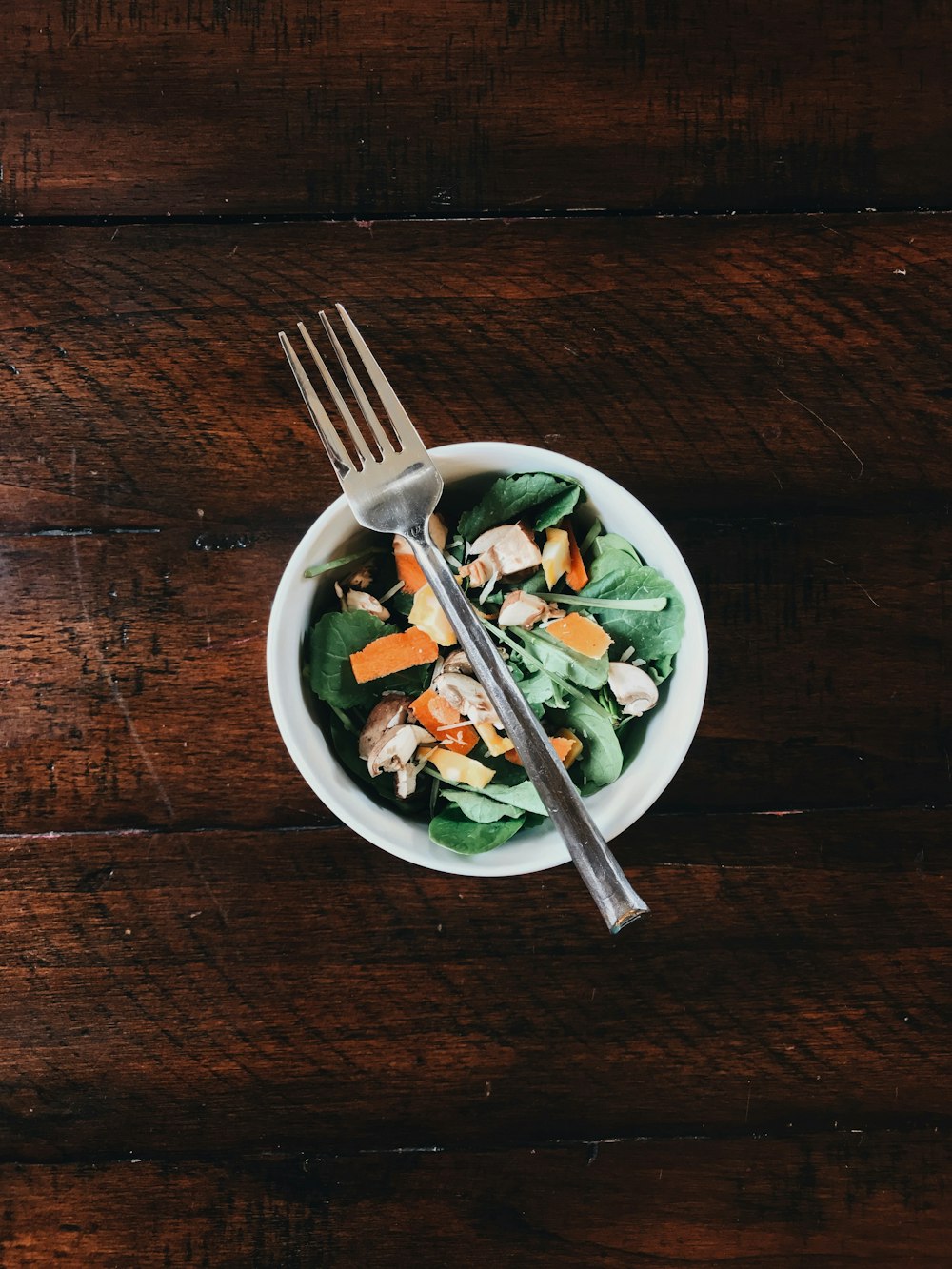 fork on round white bowl with vegetable salad